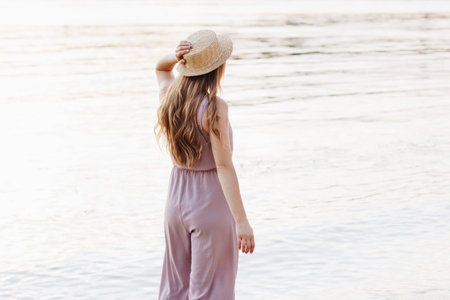 Back view of young woman with beautiful long hair wearing straw hatの写真素材