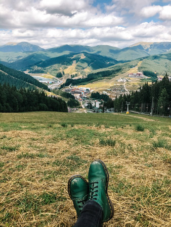 Old green boots in front of mountain viewの写真素材