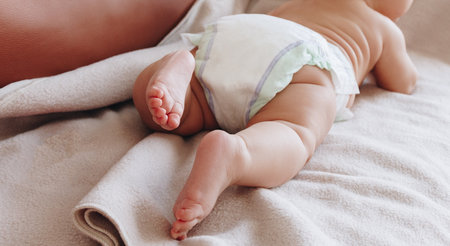 Newborn baby in diaper lying on beige plaidの写真素材