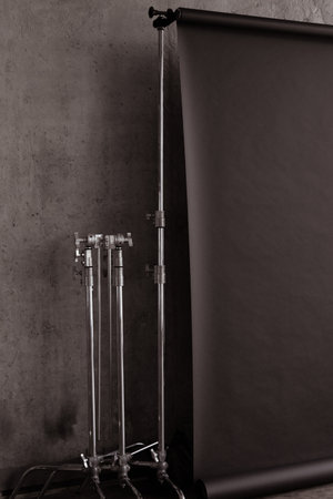 professional photo studio interior. Photography tripods and racks with black paper rollの写真素材