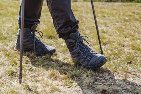 Hiker man with trekking sticks climbing on mountain trailの写真素材