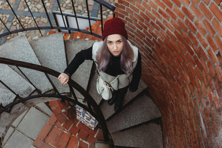 Beautiful young woman standing on spiral staircase outdoorの写真素材