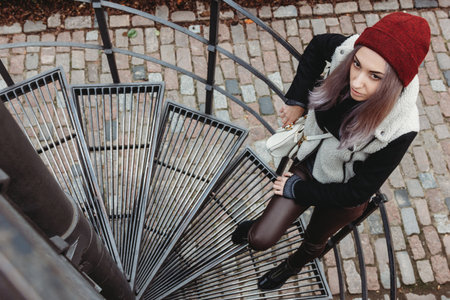 Beautiful young woman standing on spiral staircase outdoorの写真素材