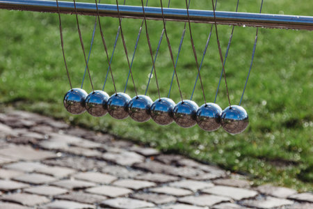 Newton cradle with balancing pendulum of silver metal balls outdoorの写真素材