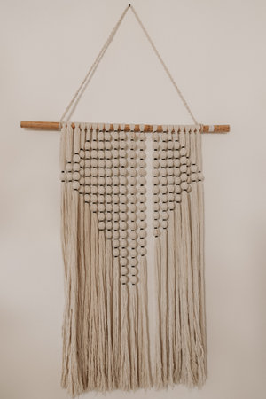 Handmade cotton macrame decoration hanging on a white wallの写真素材