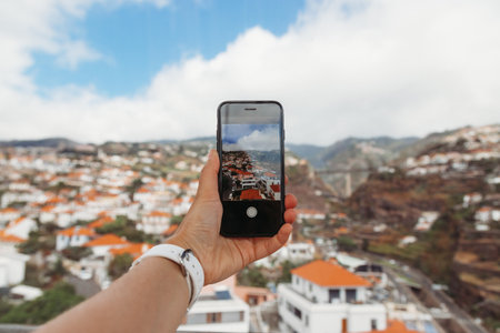 Girl taking pictures on mobile phone of Funchal city, Madeira Island, Portugalの写真素材