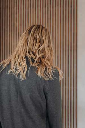 Back view of a blonde woman with wavy hair wearing grey blazerの写真素材