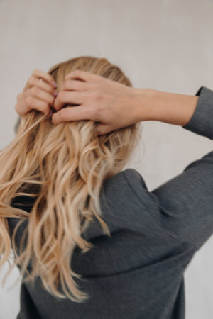 Blur image of a back view of a blonde woman with wavy hair wearing grey blazerの写真素材