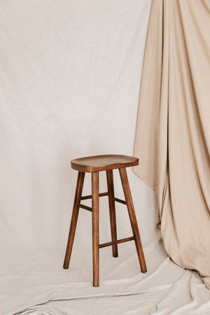 Wooden bar stool on beige textile background
