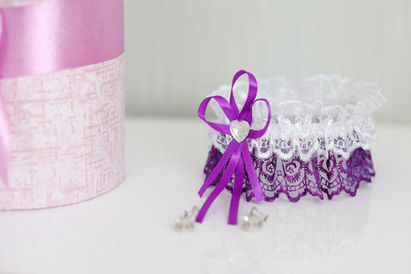 Wedding purple garter and flowers on a white tableの写真素材