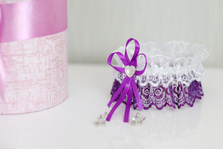 Wedding purple garter and flowers on a white table