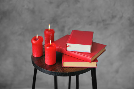 Red books and red candles on a wooden small book table. Design in the interior.の写真素材