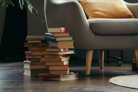 Old books next to the reading chair are stacked on the floor.の写真素材