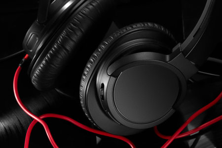 Close-up of black headphones with a red wire on a black matte background of vinyl records.の写真素材