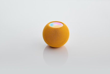 Smart round speaker in yellow color isolated on white.