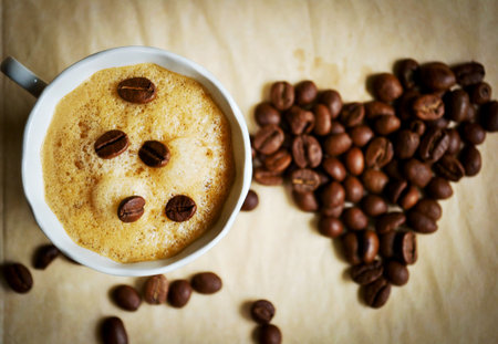 Top view of coffee cup  Coffee beans in shape of heart  Focus only on cup  Vignette added