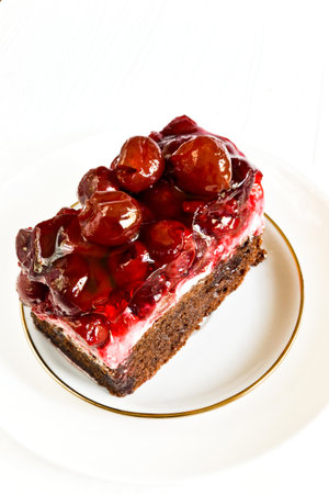 Layer cake with sweet cherries on a plate. Tasty treats to a cup of tea.