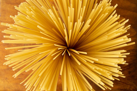 Ingredients for Italian cuisine: raw spaghetti on a wooden background