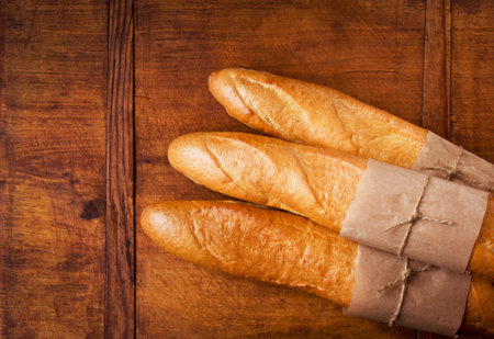 Freshly baked French baguettes on dark wooden table with copy space, top view