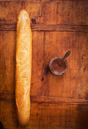 Freshly baked French baguette and chocolate on dark wooden table, still-lifeの写真素材