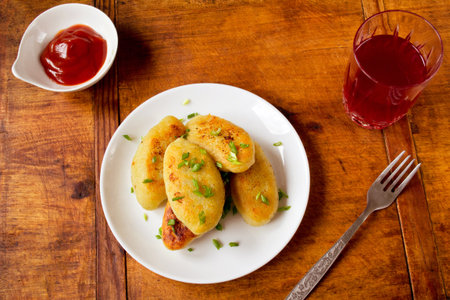 Potato patties with ketchup and juice on dark wooden background