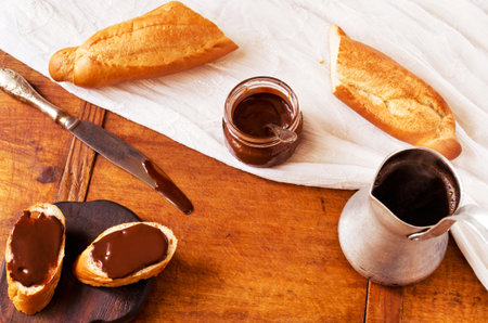 Breakfast with freshly baked French baguette, hot coffee and chocolate ganache on wooden tableの写真素材