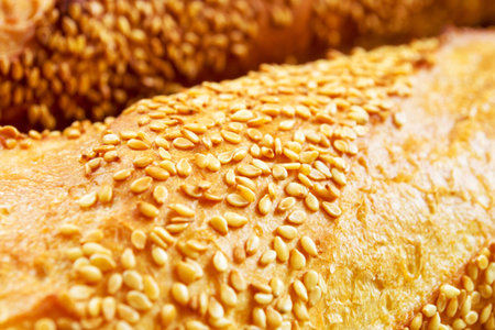 Freshly baked bread with golden crust and sesame seeds, close-upの写真素材