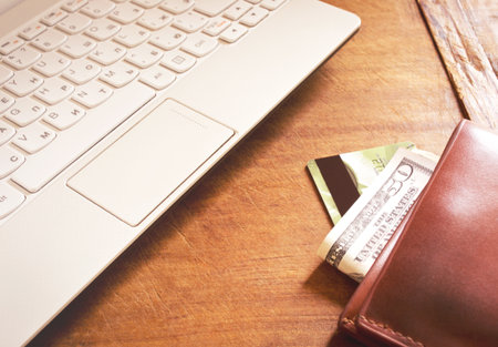 Working desk with white laptop and wallet on the wooden table
