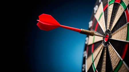 Red dart hitting the bullseye on a dartboard, symbolizing accuracy, precision, success, and business goal achievement in perfect focus.の素材