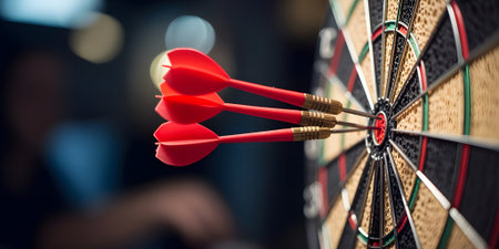 Three red darts hit the bullseye on a dartboard, representing precision, achievement, and hitting your goals.の素材