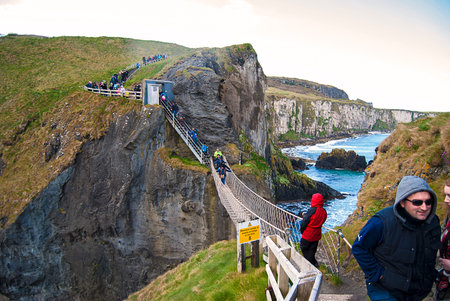 Carrick-a-Rede Rope Bridge, a popular tourist destination in Northern Ireland. Tourists passing the bridge.のeditorial素材