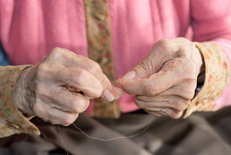 Detail of the hands of a senior person sewingの写真素材