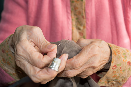 Detail of the hands of a senior person sewingの写真素材