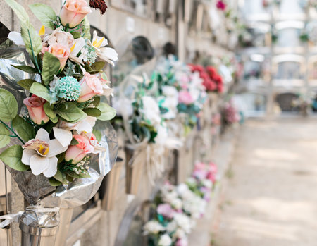 Barcelona, Spain - April 30, 2019. - Details of tombs and burial niches in formation of several floors adorned with typical flowers of traditional Spanish cemeteries, in the local cemetery of the city of Mataro.の写真素材