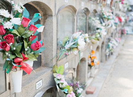 Barcelona, Spain - April 30, 2019. - Details of tombs and burial niches in formation of several floors adorned with typical flowers of traditional Spanish cemeteries, in the local cemetery of the city of Mataro.の写真素材