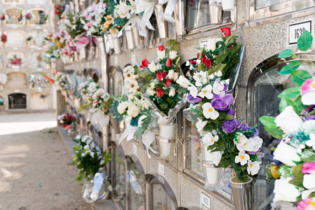 Barcelona, Spain - April 30, 2019. - Details of tombs and burial niches in formation of several floors adorned with typical flowers of traditional Spanish cemeteries, in the local cemetery of the city of Mataro.の写真素材