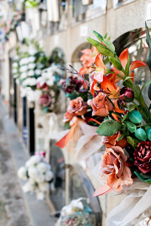 Barcelona, Spain - April 30, 2019. - Details of tombs and burial niches in formation of several floors adorned with typical flowers of traditional Spanish cemeteries, in the local cemetery of the city of Mataro.の写真素材