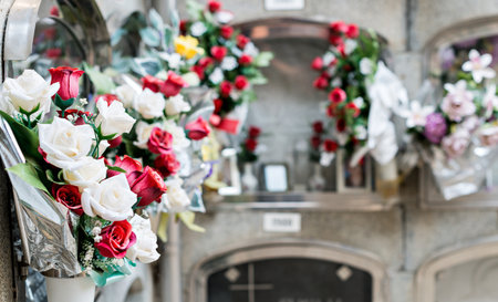 Barcelona, Spain - April 30, 2019. - Details of tombs and burial niches in formation of several floors adorned with typical flowers of traditional Spanish cemeteries, in the local cemetery of the city of Mataro.の写真素材