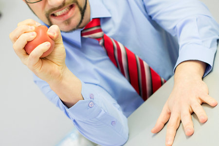 Angry boss squeezing stress ball in the office.の写真素材