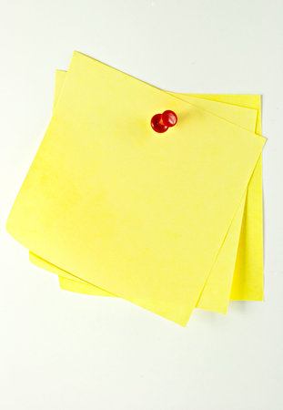 Three yellow sticky paper pinned with a pin at a white background.の写真素材