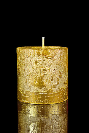 Candle gold on a black reflective background.の写真素材