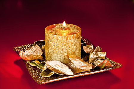 Richly decorated Christmas candle on the golden dish of golden petals ornament.の写真素材