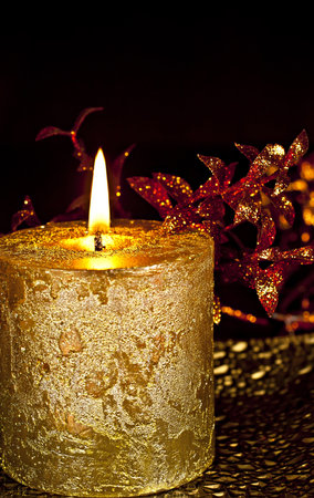 Christmas Decor, a burning candle with glossy leaves on a dark background.の写真素材