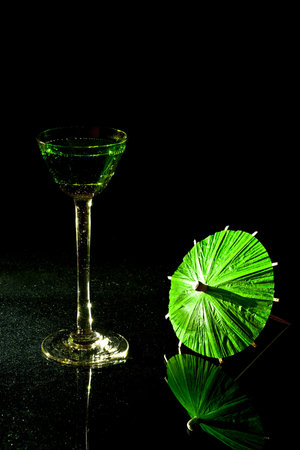 On a black background with green cocktail glass vermouth and a green parasol.の写真素材