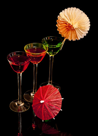 On a black background, three cocktail glasses decorated with parasols.の写真素材