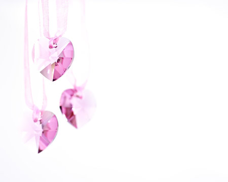 Three pink crystal hearts on a white background.の写真素材