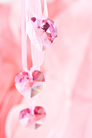 Three crystal hearts on a pink background.の写真素材