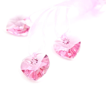 Three pink crystal hearts on a white background.の写真素材