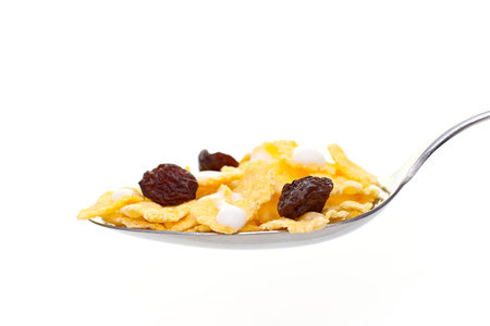 Spoon the corn flakes, milk and raisins. On a white background.