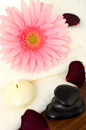 Aromatherapy relaxation, bath towels and a pink flower with a candle and massage stones.の写真素材